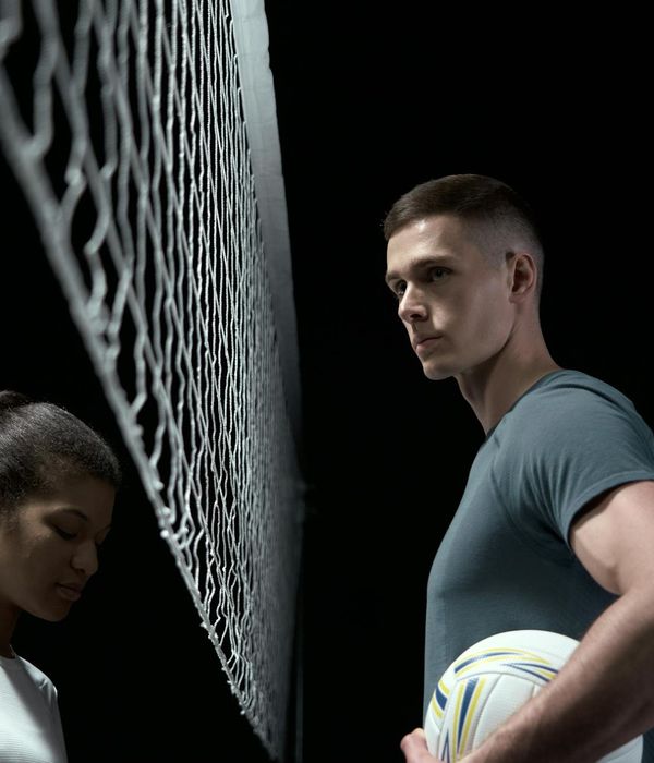 Man performing a strength exercise in a dark studio with azure light.